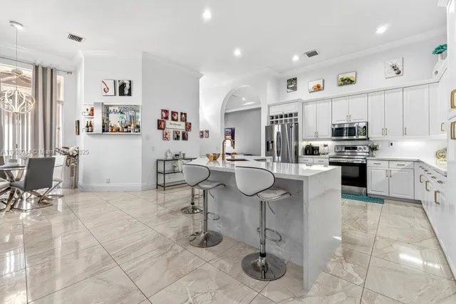 a kitchen with stainless steel appliances kitchen island granite countertop a table and chairs in it