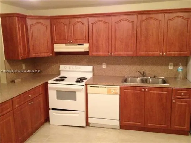 a kitchen with granite countertop wooden cabinets and white appliances