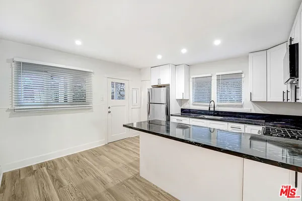 a large kitchen with stainless steel appliances granite countertop a sink and cabinets