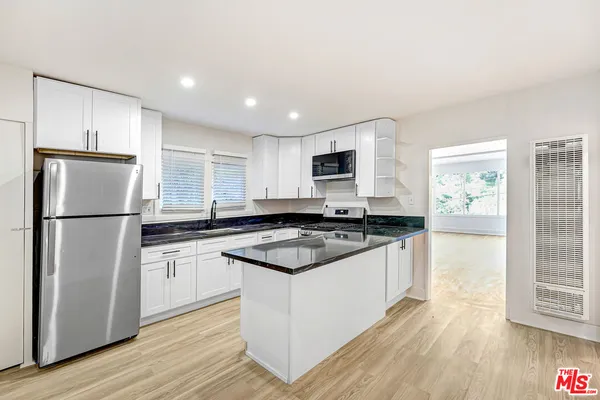 a kitchen with stainless steel appliances granite countertop a stove a refrigerator and a microwave