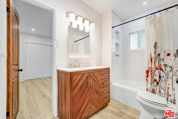 a bathroom with a bathtub sink vanity mirror and toilet