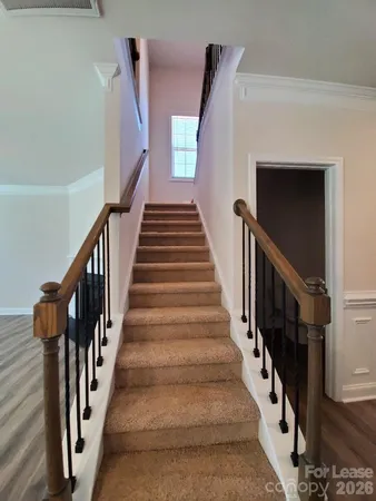 a view of staircase with lots of frames on wall and wooden floor