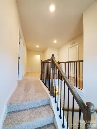 a view of a hallway with wooden floor and stairs