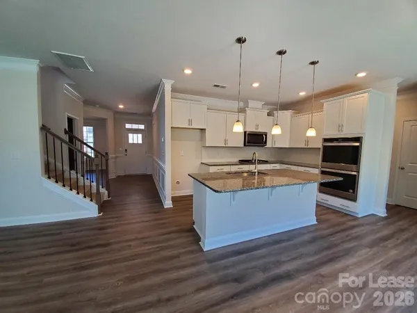 a large kitchen with kitchen island a island a stove a center island a refrigerator and a wooden floor