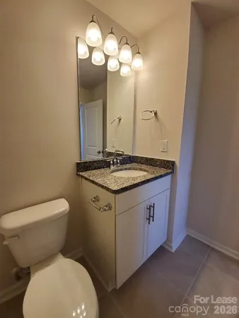 a bathroom with a granite countertop toilet sink and mirror
