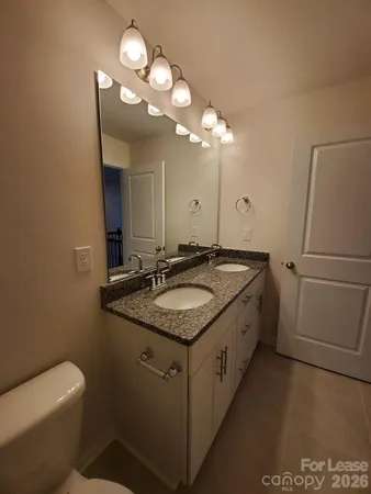 a bathroom with a granite countertop sink a toilet and a mirror