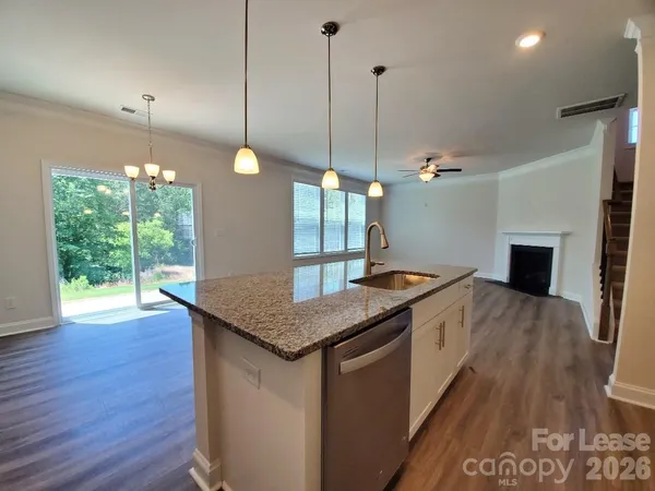 a kitchen with stainless steel appliances granite countertop a stove a sink a refrigerator a center island with wooden floor and cabinets