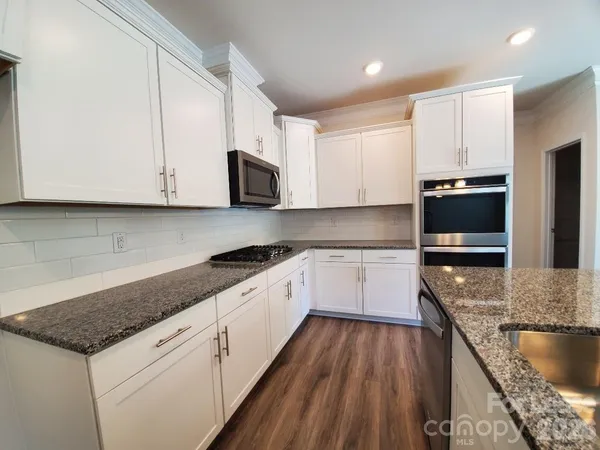 a kitchen with granite countertop a sink a stove and cabinets