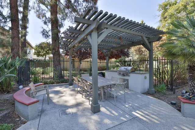 a view of a patio with table and chairs potted plants and large tree