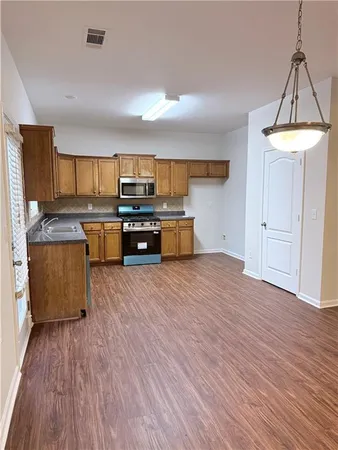 a large kitchen with wooden floors and stainless steel appliances