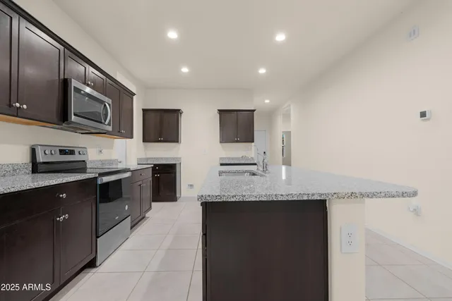 a large kitchen with stainless steel appliances granite countertop a stove a sink and a microwave