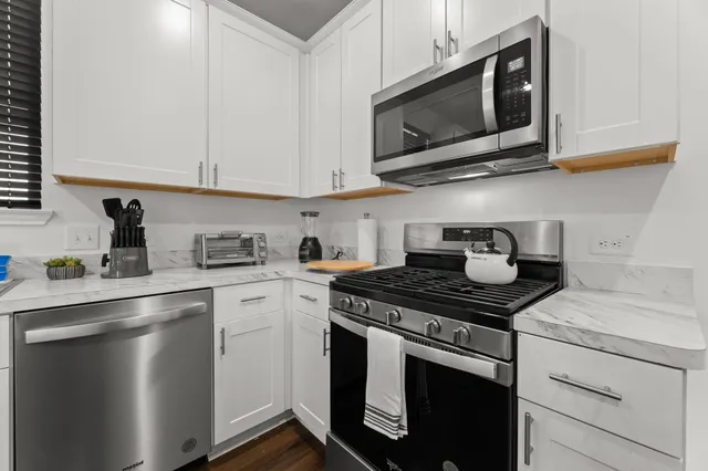a kitchen with stainless steel appliances granite countertop a sink stove top oven and cabinets