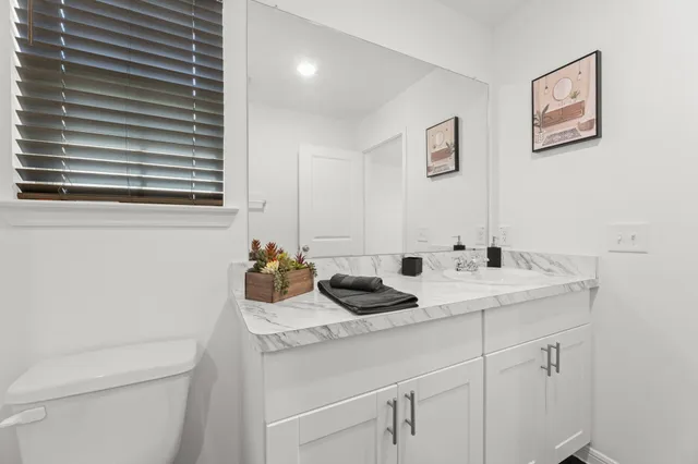 a bathroom with a granite countertop sink and a toilet