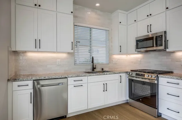 a kitchen with granite countertop white cabinets and white appliances