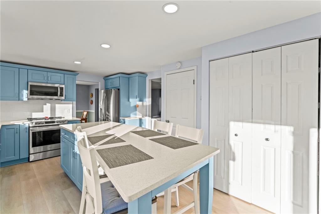 1256 Manor Drive Pittsburgh, PA 15241 - Photo 10 of 35 a large kitchen with kitchen island a stove a sink a refrigerator and white cabinets with wooden floor