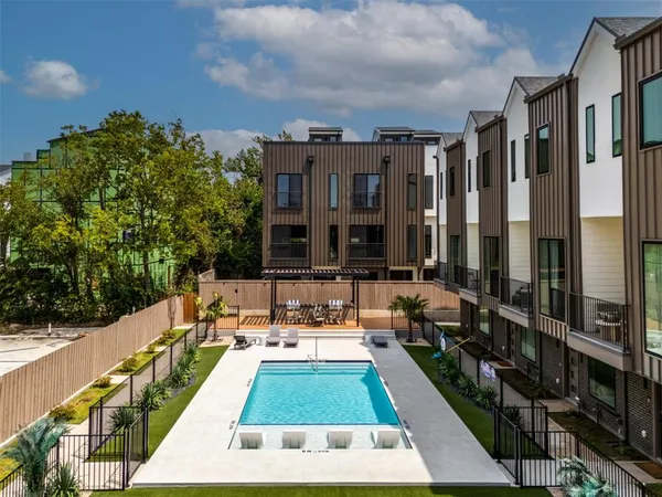 a view of swimming pool in front of residential houses with outdoor seating