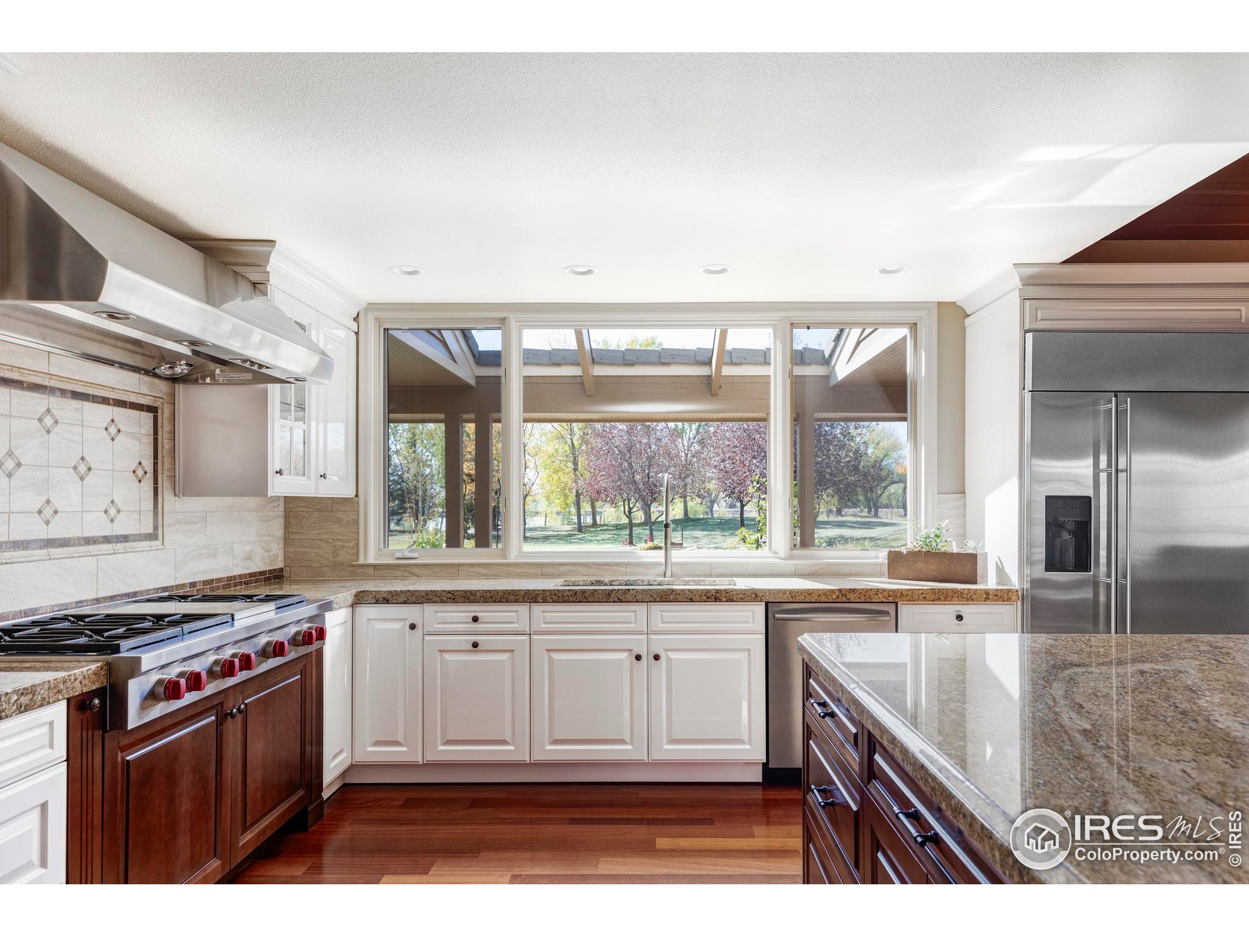 9402 Crystal Lane Longmont, CO 80503 - Photo 13 of 32 a kitchen with stainless steel appliances granite countertop a stove a sink and a granite counter tops with white cabinets next to a window