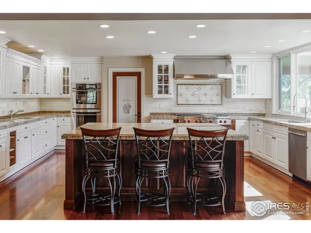 a kitchen with stainless steel appliances granite countertop a table chairs sink and cabinets