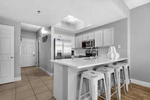 a kitchen with stainless steel appliances a sink a stove a refrigerator cabinets and a dining table