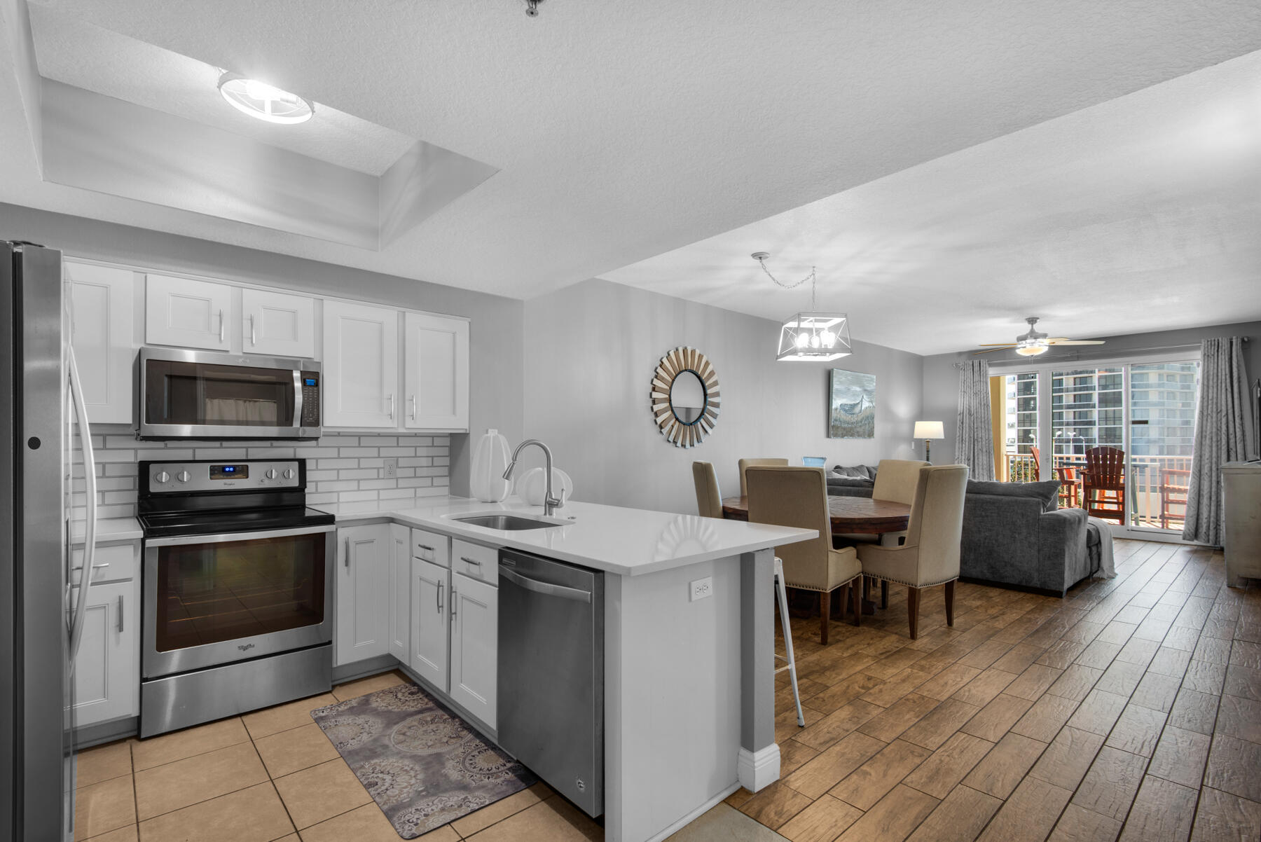 112 Seascape Drive, Unit 402 Miramar Beach, FL 32550 - Photo 4 of 31 a kitchen with stainless steel appliances granite countertop a stove top oven a sink dishwasher a dining table and chairs with wooden floor