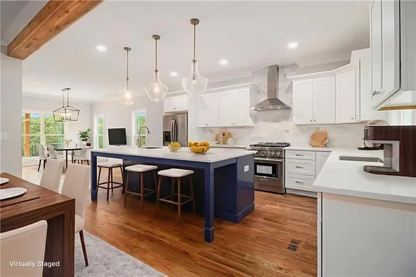 a open kitchen with stainless steel appliances granite countertop a stove a sink dishwasher a microwave oven and a dining table with wooden floor
