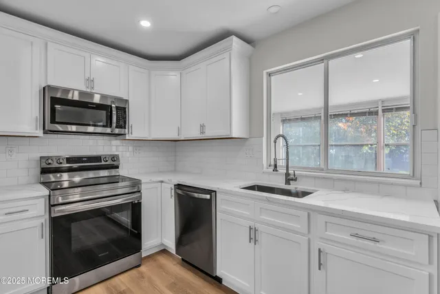a kitchen with cabinets stainless steel appliances a sink and a window