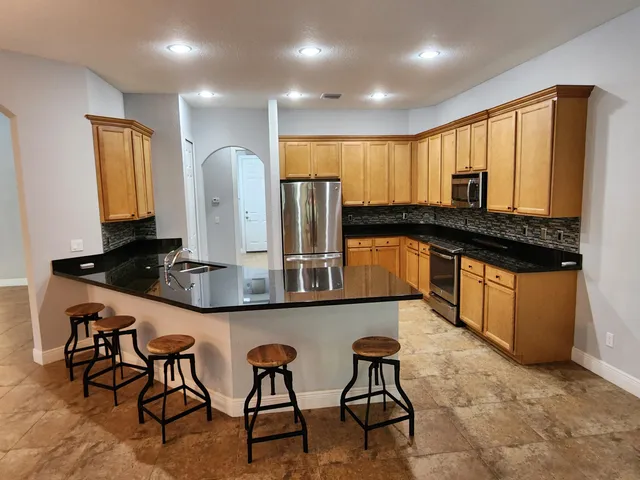 a kitchen with stainless steel appliances granite countertop a refrigerator and a stove top oven