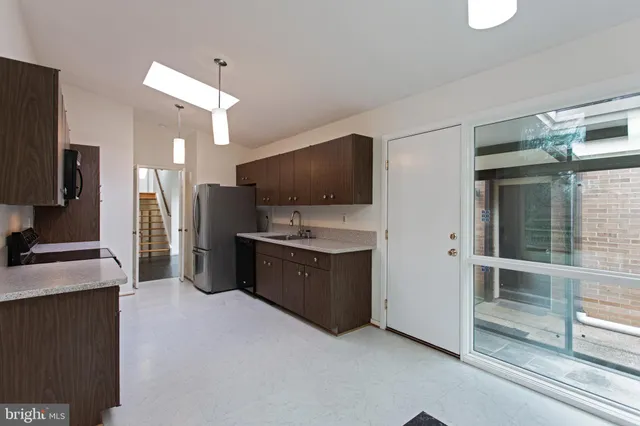 a large living room with stainless steel appliances kitchen island granite countertop a refrigerator and a stove top oven