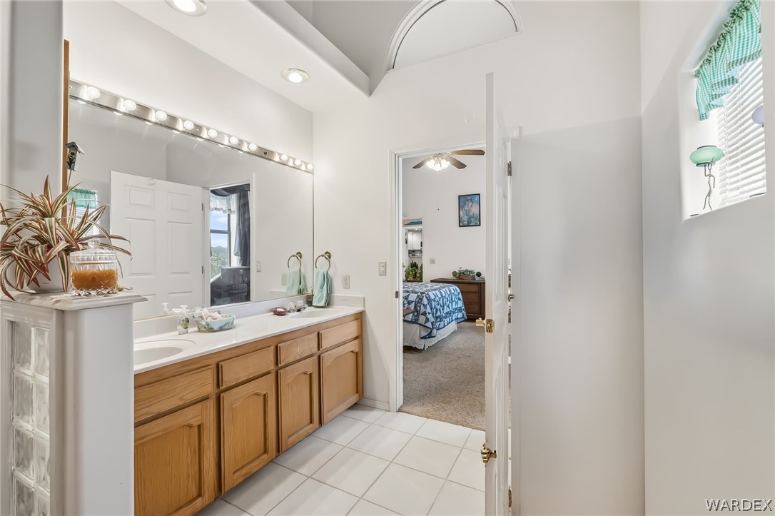 2401 North Stephan Road Kingman, AZ 86401 - Photo 47 of 92 Spacious vanity area featuring dual sinks, a large wall-mounted mirror with overhead strip lighting, ample wood cabinetry, and a tile floor