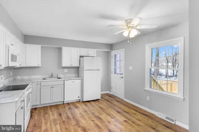 a kitchen with white cabinets and window