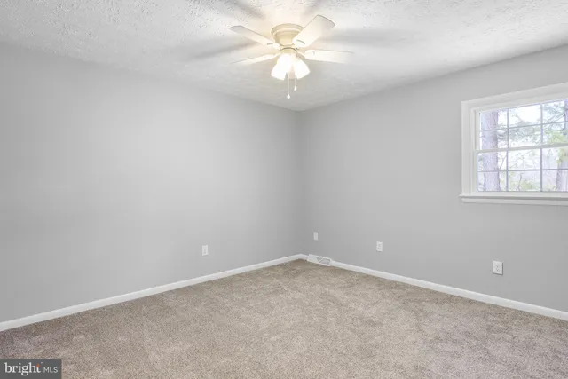 an empty room with a window and a chandelier fan
