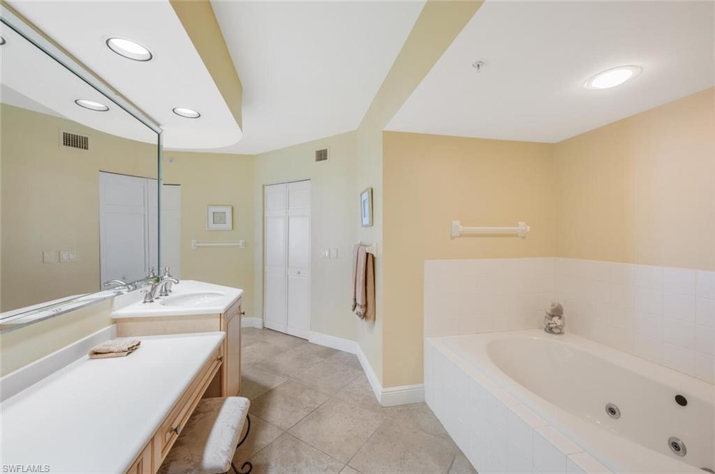 20 Seagate Drive, Unit 803 Naples, FL 34103 - Photo 28 of 44 a bathroom with a tub sink and mirror