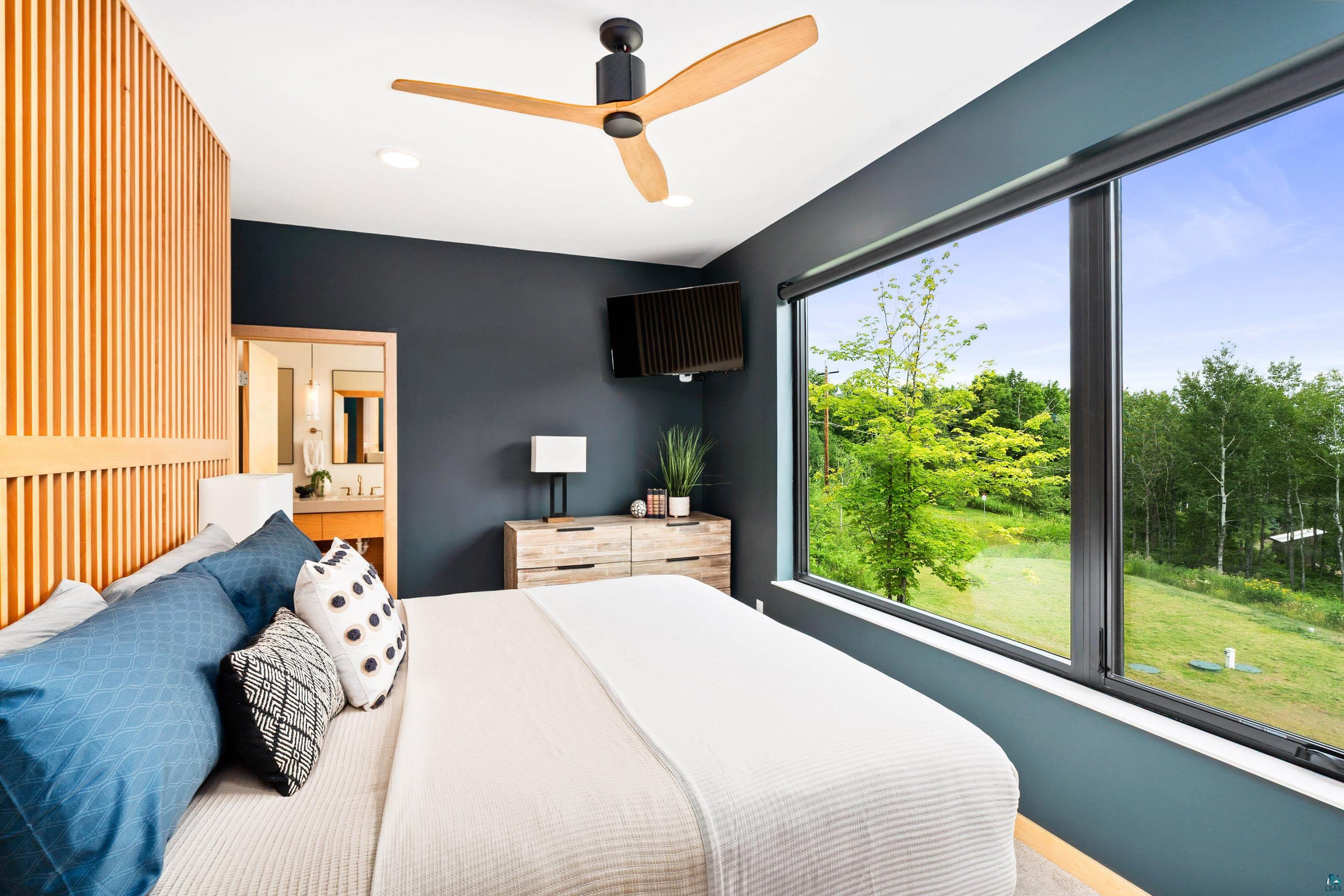 814 Pleasant View Road Duluth, MN 55803 - Photo 19 of 49 Bedroom featuring a full-width panoramic window, wood-slat accent wall, and a modern ceiling fan with wood-finish blades