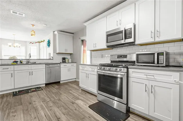 a kitchen with stainless steel appliances granite countertop a stove a sink and a microwave