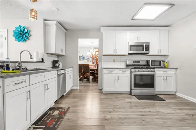 a kitchen with stainless steel appliances granite countertop a stove a sink and a microwave