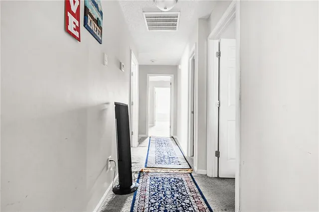a view of a hallway with wooden floor and a bathroom