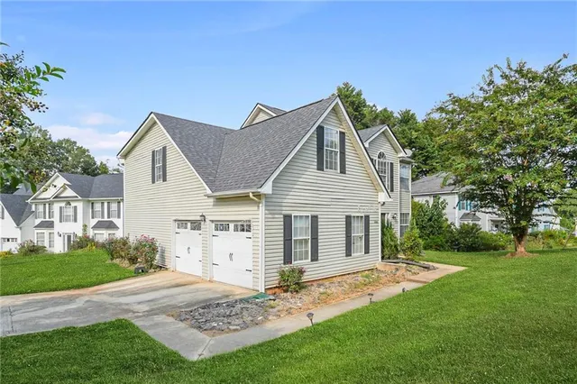 a view of a yard in front of a house with plants and large tree