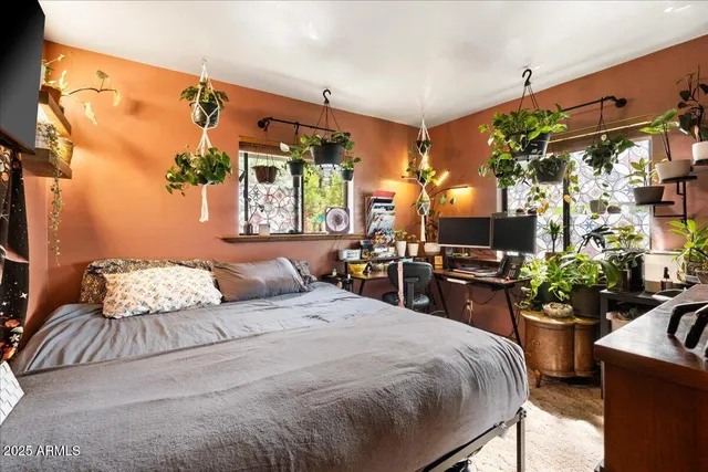 a bedroom with a bed a potted plant and a large mirror on the dresser