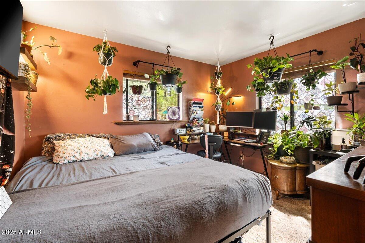 17040 Bowstring Road Munds Park, AZ 86017 - Photo 13 of 18 a bedroom with a bed a potted plant and a large mirror on the dresser