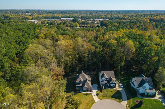 an aerial view of a house with swimming pool big yard and large trees