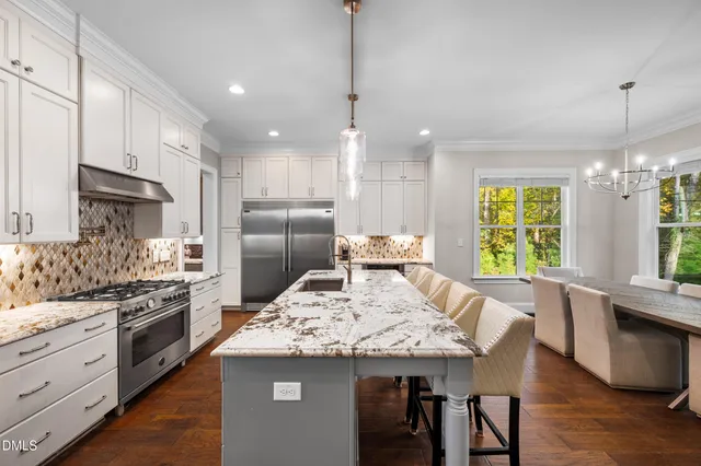 a kitchen with stainless steel appliances kitchen island granite countertop a refrigerator a oven a sink with a dining table and chairs