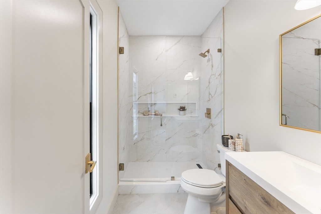 142 Metropolitan Avenue, Unit 2 Boston, MA 02131 - Photo 10 of 13 a bathroom with a granite countertop toilet a sink and a mirror