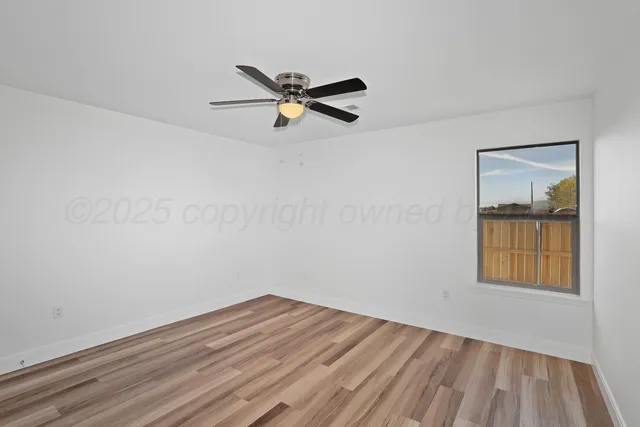 an empty room with a window and a ceiling fan