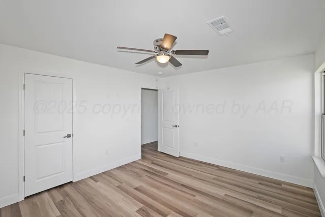 a view of a room with wooden floor and a ceiling fan