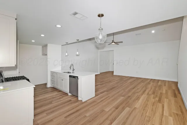 a large kitchen with stainless steel appliances a large counter top a sink a refrigerator and a stove