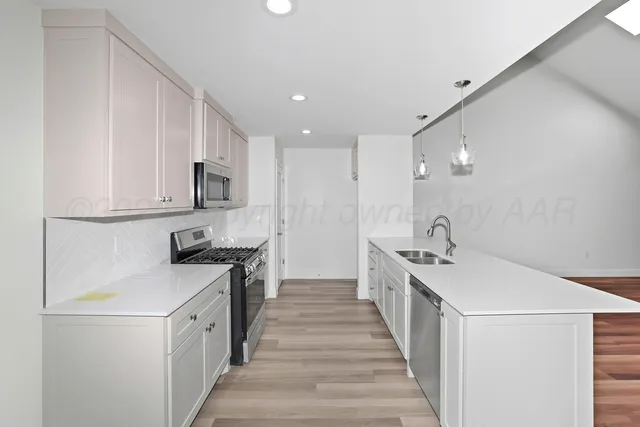 a kitchen with white cabinets sink and stove