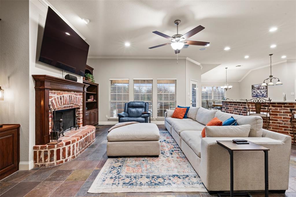 517 Chado Lane Robinson, TX 76706 - Photo 5 of 40 Living area with ornamental molding, a brick fireplace, stone tile floors, a ceiling fan, and suspended lighting