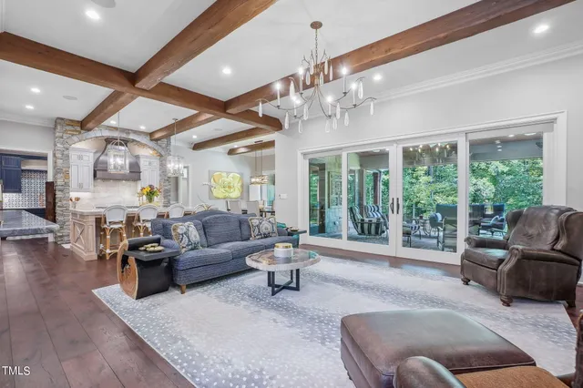 a large white kitchen with stainless steel appliances kitchen island granite countertop a table chairs in it and a wooden floor