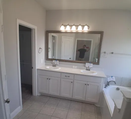 a spacious bathroom with a double vanity sink mirror and bathtub