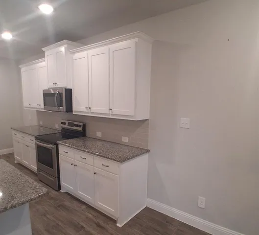 a kitchen with granite countertop white cabinets and stainless steel appliances